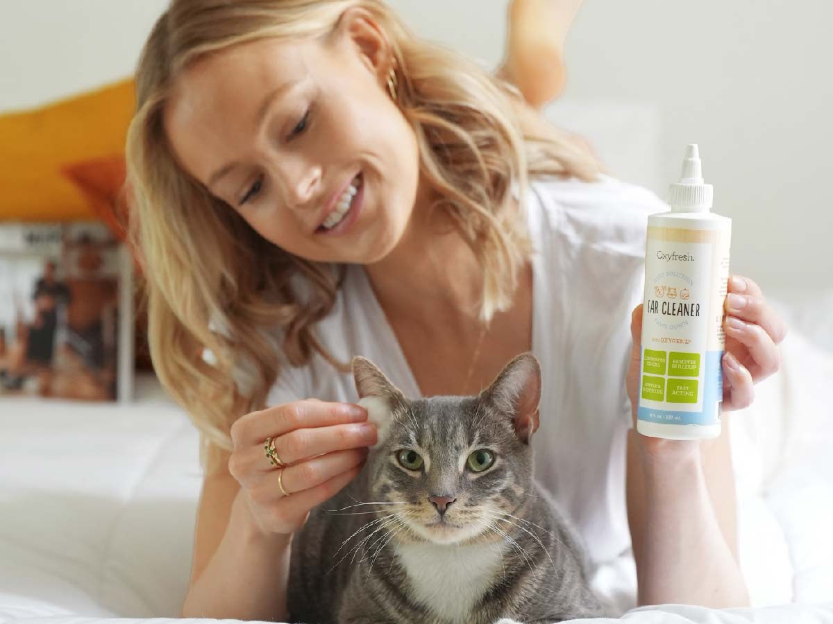 oxyfresh-earcleaner_smiling-woman-using-cat-and-dog-ear-cleaning-solution-on-adorable-cat-for-stinky-pet-ears
