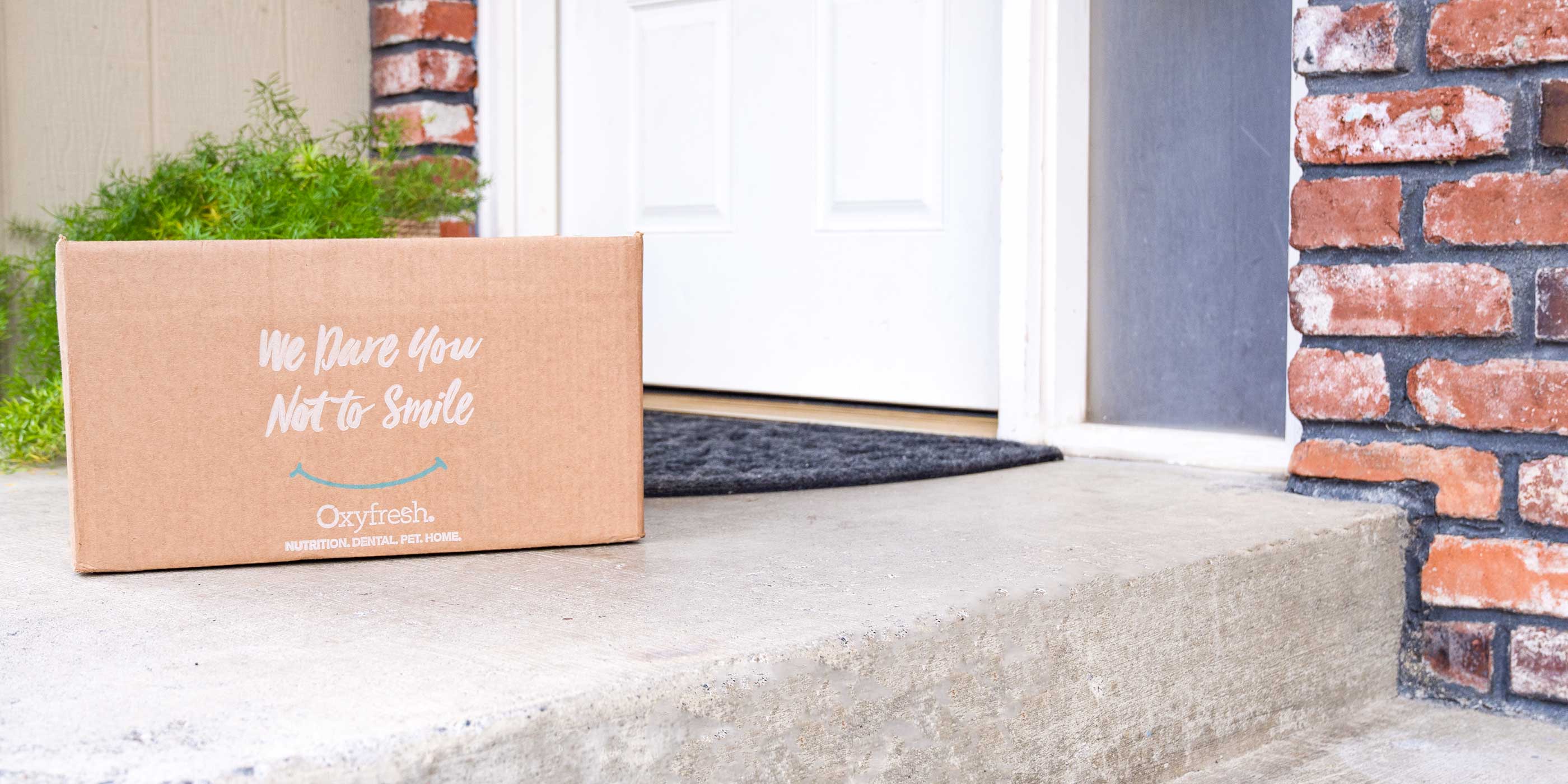 oxyfresh shipping box on a front porch which says "we dare you not to smile"