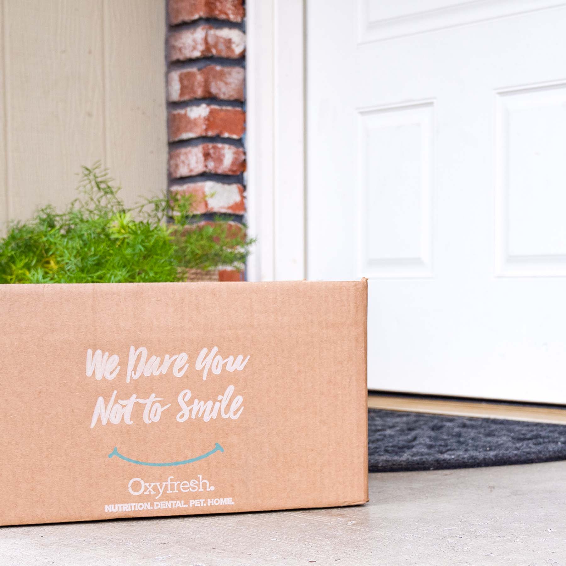 oxyfresh shipping box on a front porch which says "we dare you not to smile"